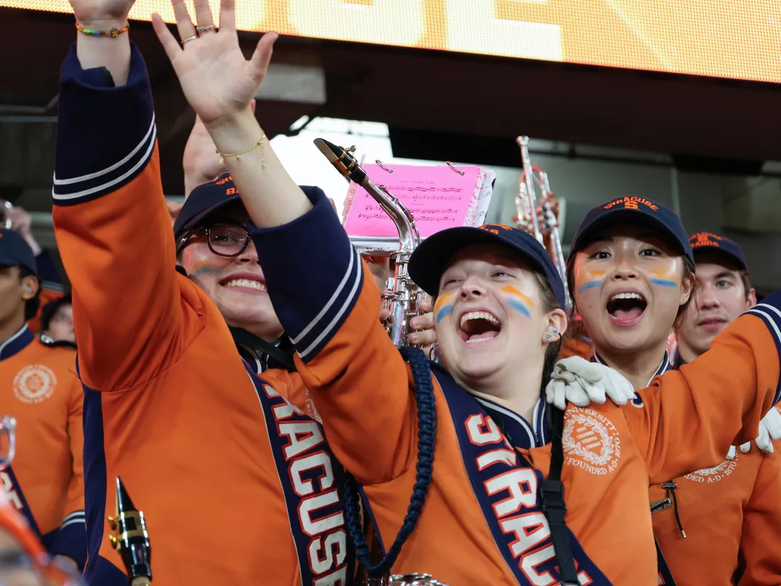 Members of the Marching Band raise up their arms.