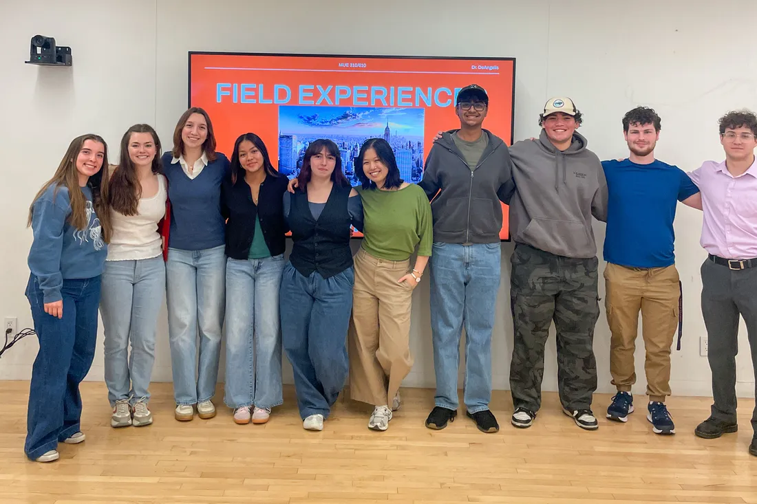 A group of students stand together in a classroom.