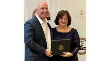Ida Tili-Trebicka holds a rectangular award and poses with a man in a suit.