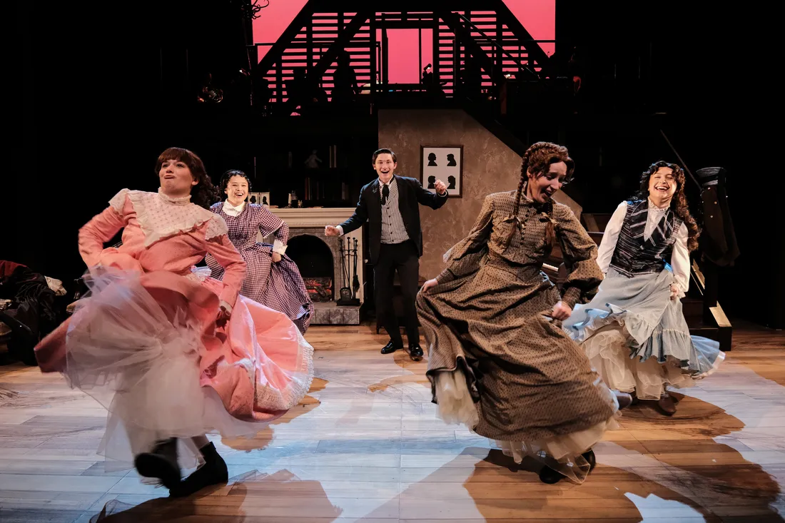 A group of students in costume perform a dance number on a stage.